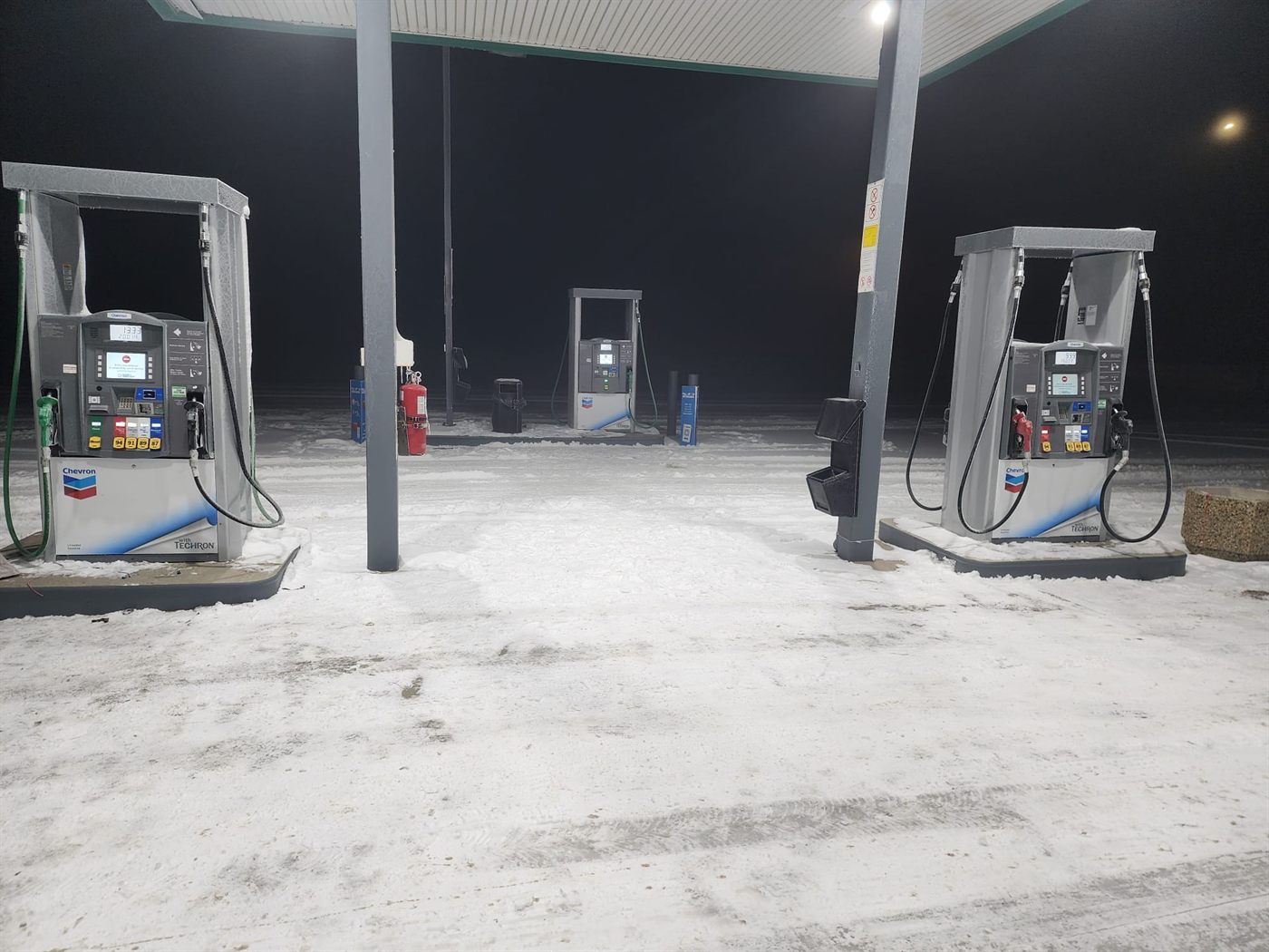 Chevron forecourt at night in snow with new dispensers under the canopy