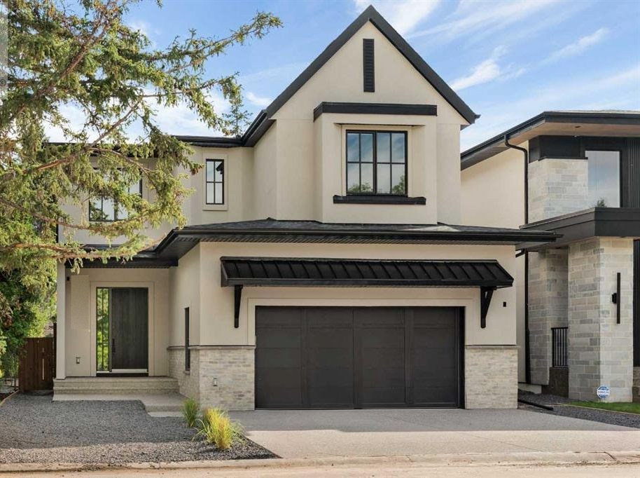 Custom home in Lakeview, Calgary with stucco and stone exterior and dark garage doors