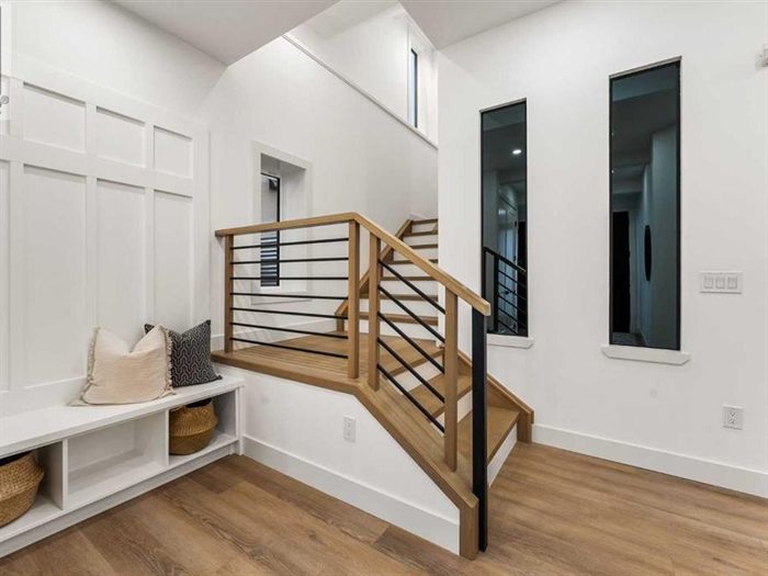 Staircase with black metal railing and recessed lighting